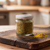 Glass jar of spice on a wooden cutting board with a blurred kitchen background