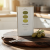 Terra Medi olive oil can on a wooden cutting board with olives and rosemary.