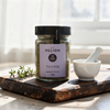 Jar of Mt. Pelion Thyme on a wooden board with a mortar and pestle.