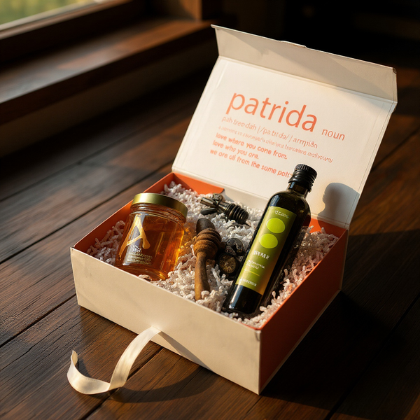 Gift box with honey, olive oil,olive oil pourer and a gift box labeled 'patrida' on a wooden surface.
