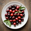 White plate with red and black olives on a brown surface